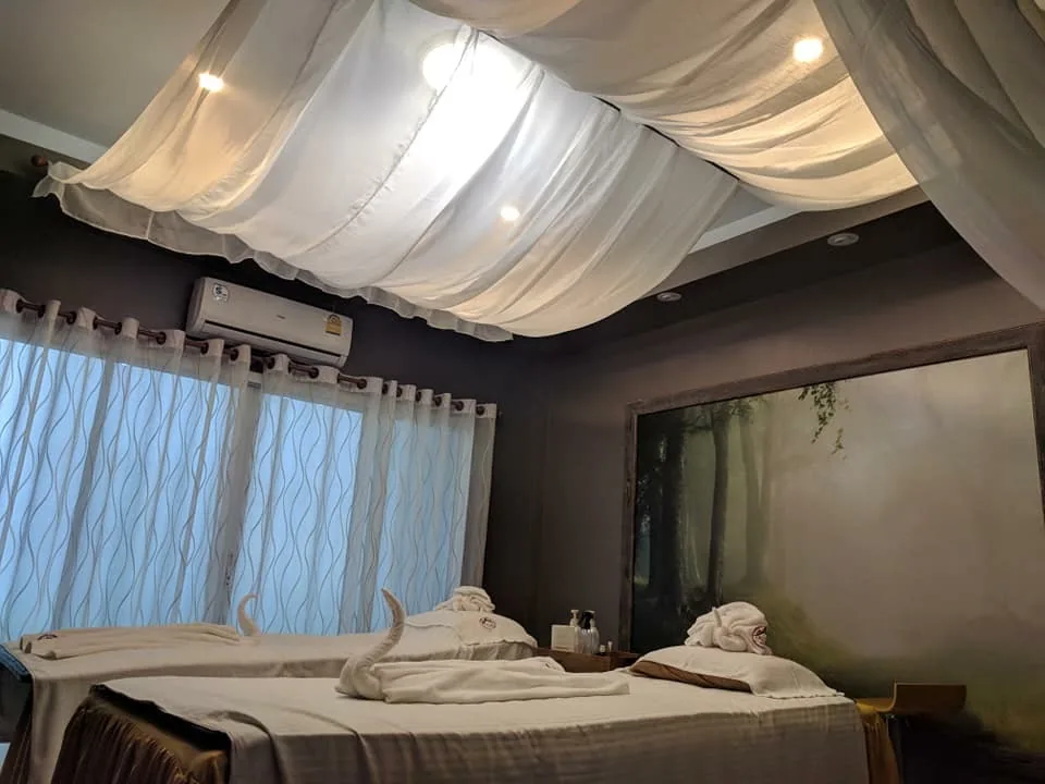 มุมกว้างของห้องทรีตเมนต์ที่เพดานมีผ้าโปร่งขาวและเตียงที่ปูผ้าพับไว้
