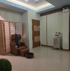 เก้าอี้นวดหนังวางอยู่ในมุมห้อง ใกล้อ่างที่วางบนพื้นและอุปกรณ์ของร้าน